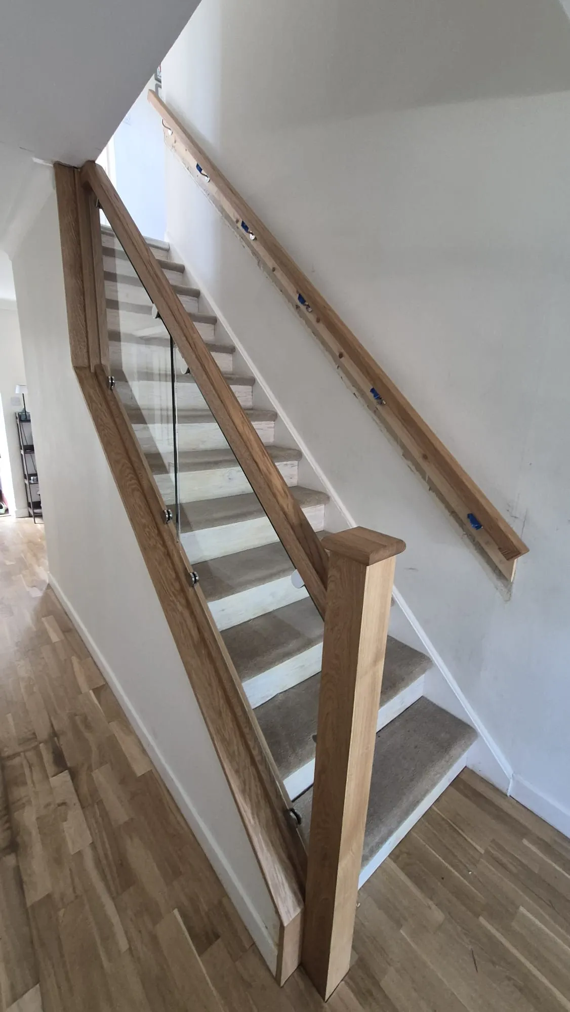 Bespoke oak stair with a clamped glass balustrade, square oak newel and oak wall handrail
