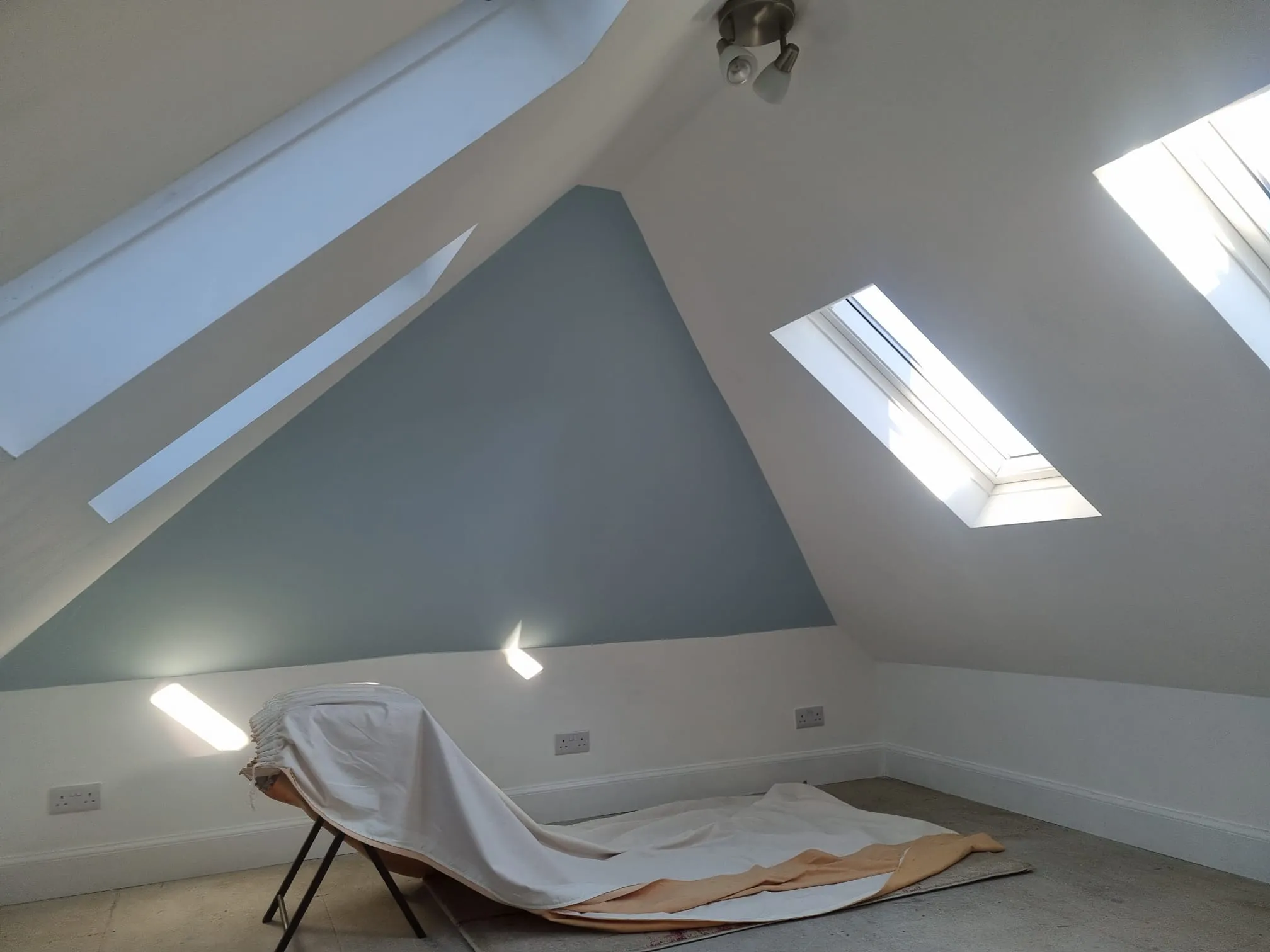 Converted loft room with three skylights, white walls, a blue gable wall and new skirting