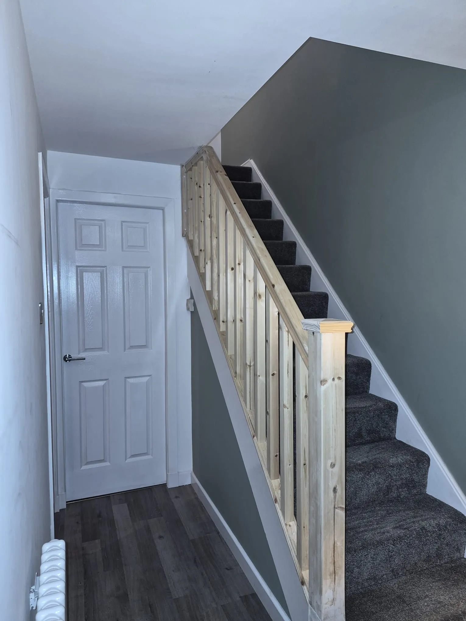New pine stair balustrade with square spindles and newel post on a grey carpeted staircase