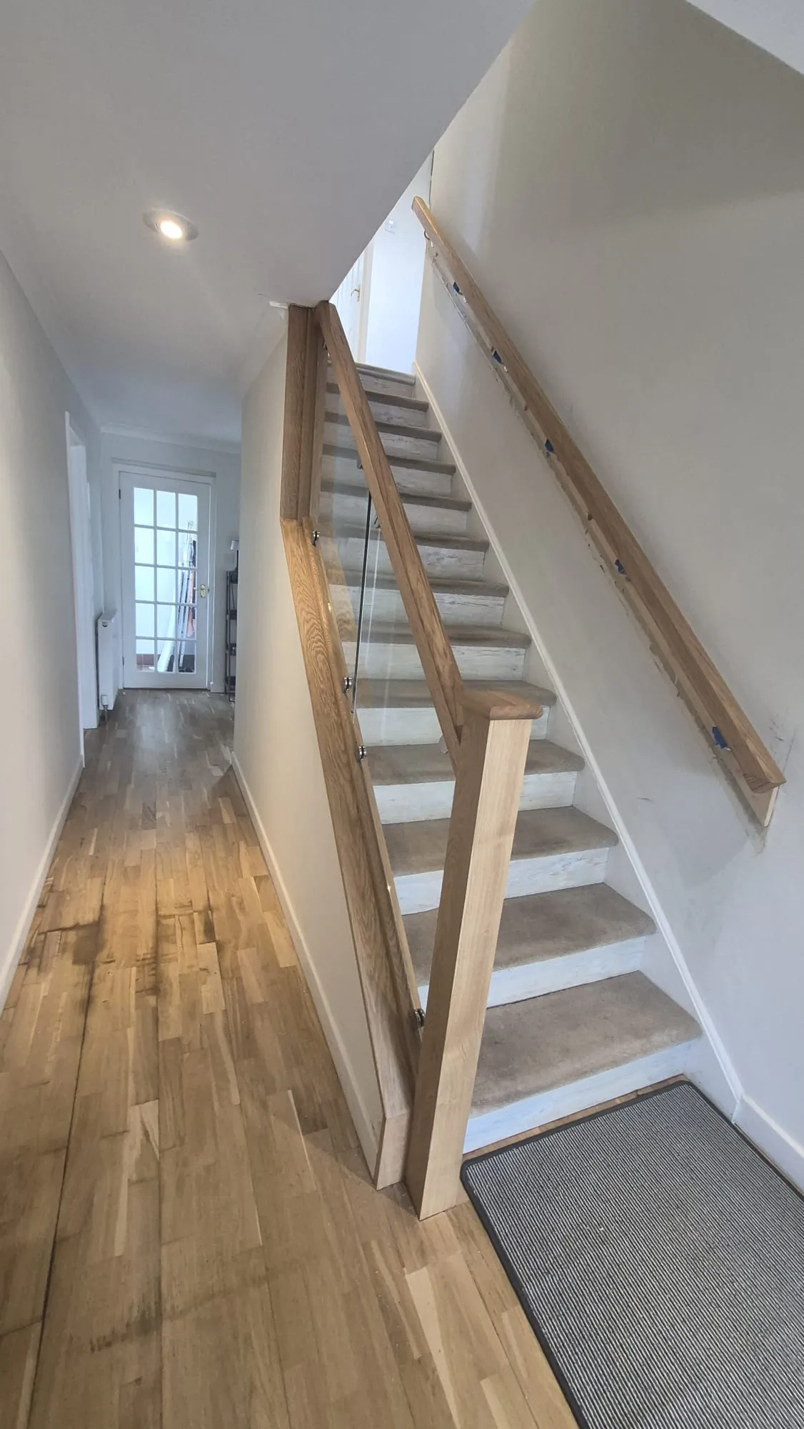 Oak and frameless glass stair balustrade with square oak newel and matching wall handrail