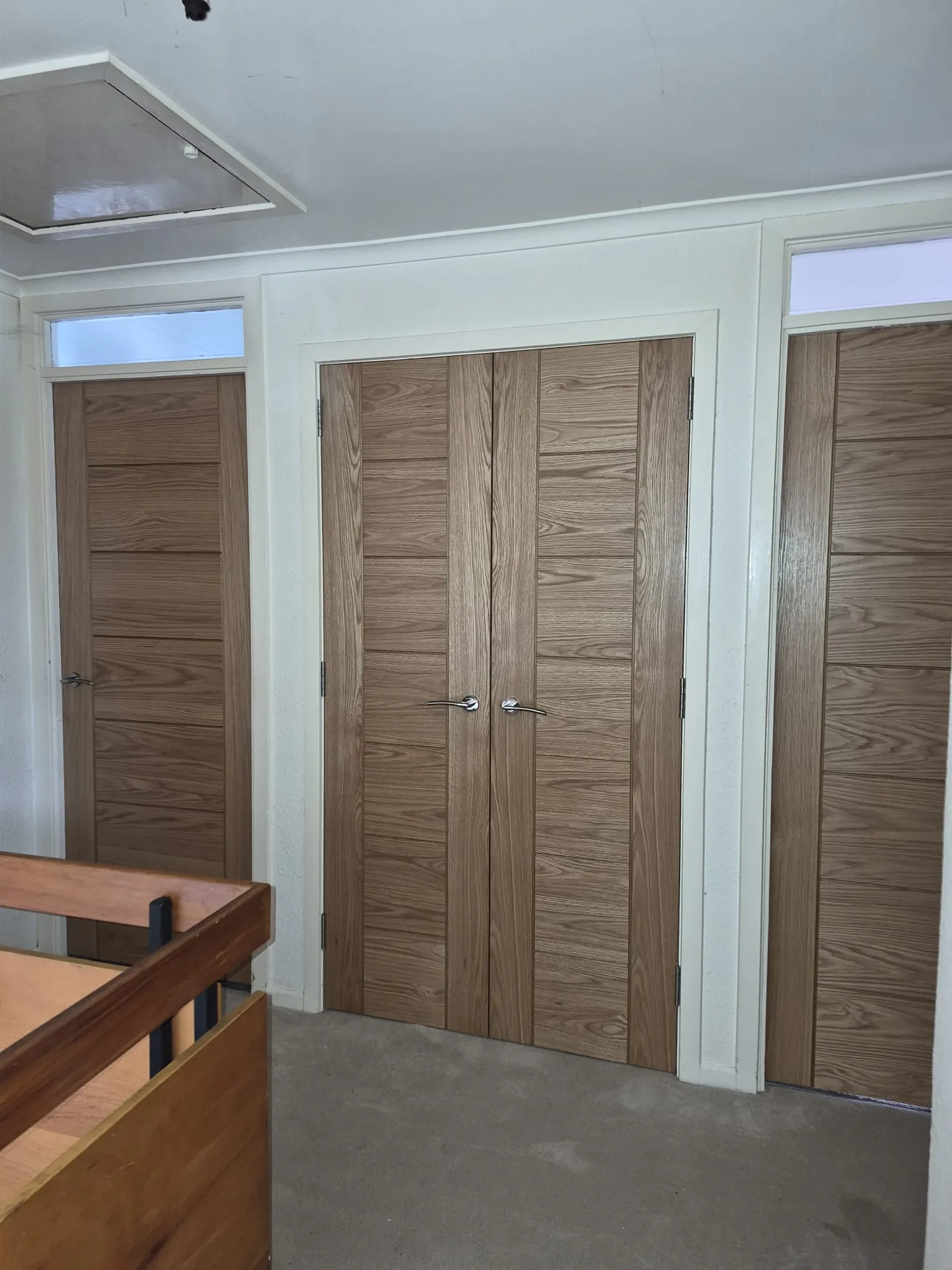 Oak veneer double doors and matching internal doors with chrome handles on a landing