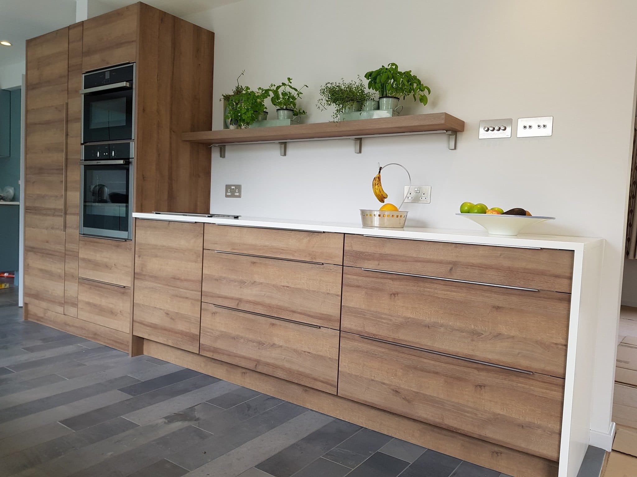 Wood-effect fitted kitchen with floating shelves and integrated ovens fitted by a kitchen fitter Tranent